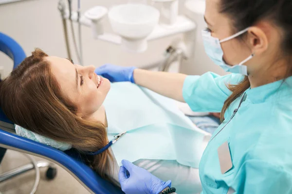Lekarz przygotowujący kobietę do zabiegu stomatologicznego w klinice — Zdjęcie stockowe