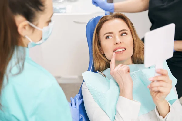 Mulher discutindo tratamento odontológico com dentista na clínica — Fotografia de Stock