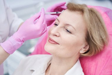 Yüz gerdirme ameliyatı yapan yaşlı bir kadına odaklanmış bir fotoğraf.