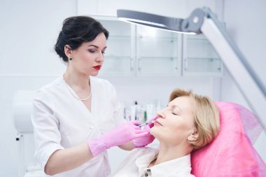 Enjeksiyonla kırışıklıkları dolduran konsantre bir tıp çalışanı.