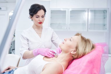 Genç güzellik uzmanı kıdemli bir hastayla çalışıyor.