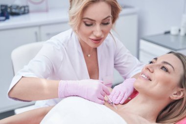 Doktor, mezoterapi sırasında kadına deri altı enjeksiyonu yapıyor.