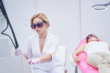 Güzellik uzmanı kadın hastayı estetik ameliyata hazırlıyor.