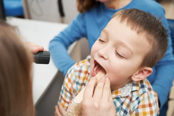 Arzt untersucht Kehle von kleinem Jungen in Klinik — Stockfoto