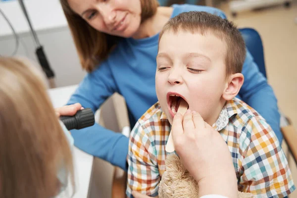Pediatra examinando a garganta da criança com depressor de língua — Fotografia de Stock