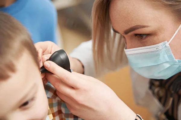 Pediatra examinando orelha infantil com otoscópio na clínica — Fotografia de Stock
