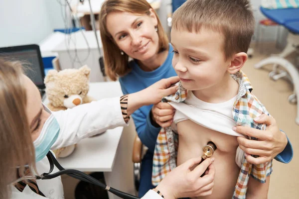 Mujer médico examinando niño con estetoscopio en la clínica — Foto de Stock