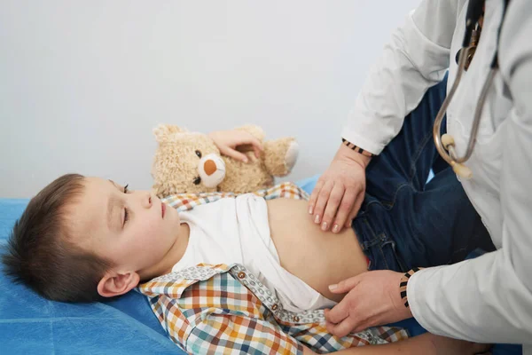 Médico examinando al niño y haciendo palpación abdominal — Foto de Stock