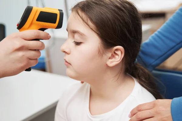 Dokter controleren kleine meisje temperatuur in de kliniek — Stockfoto