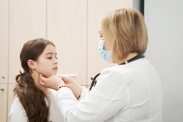 Pediatra feminino examinando linfonodos infantis na clínica — Fotografia de Stock