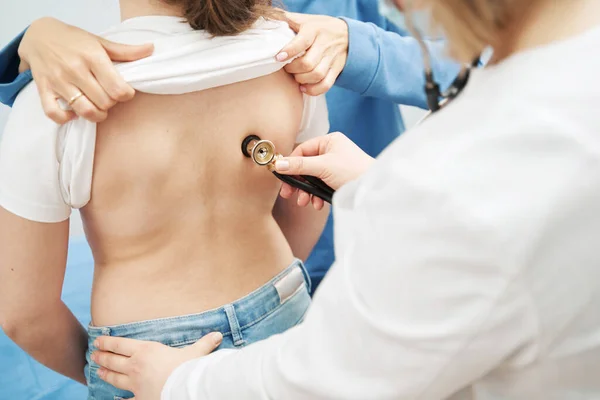 Doctor examining little girl with stethoscope in clinic — ストック写真