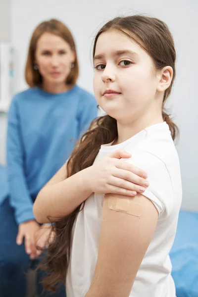 백신 접종 후에 의료용 석고로 만든 팔을 보이고 있는 어린 소녀 — 스톡 사진