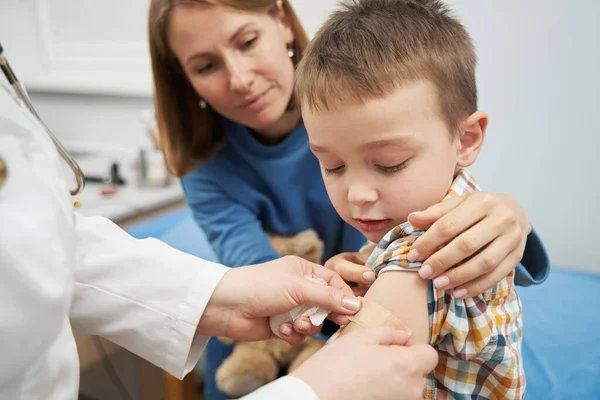 Médico que coloca gesso médico no braço da criança após a vacinação — Fotografia de Stock