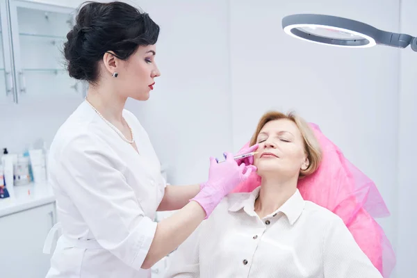 Mujer madura preocupada haciendo la inyección en la cara — Foto de Stock