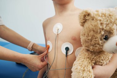Çocuk doktoru EKG tutucu monitörüyle çocuğun kalp ritmini kontrol ediyor.