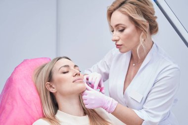 Kadınlara deri altı enjeksiyonu yapan odaklı kozmetikçi.