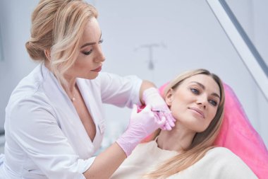 Azot eldivenli dermatolog mezoterapi prosedürü uyguluyor.