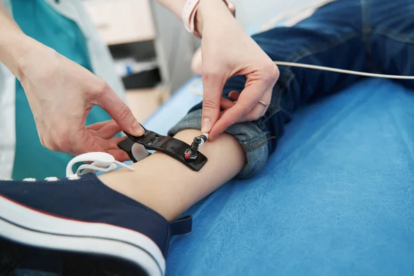 Médico manos poniendo sensor de electrocardiograma en la pierna del niño — Foto de Stock