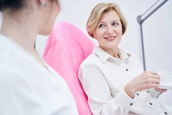 Glücklich gealterte Frau genießt Kommunikation mit Kosmetikerin — Stockfoto