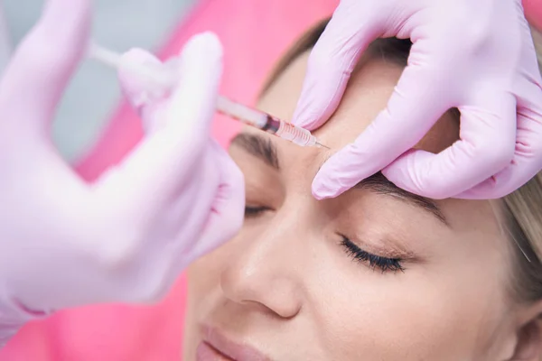 Female patient receiving dermal filler injection into glabellar line — Stock Photo, Image