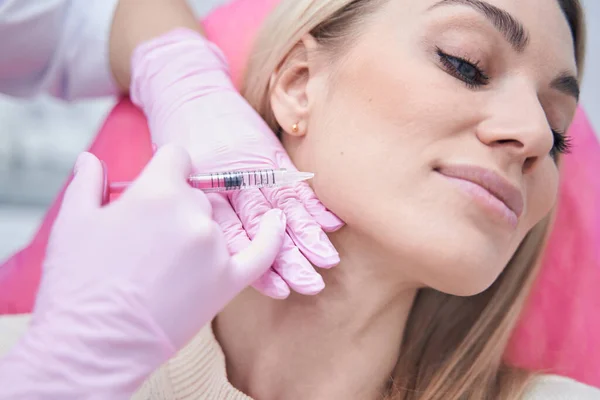Vrouwelijke krijgen wang vulmiddel injectie onder de huid van jukbeen — Stockfoto