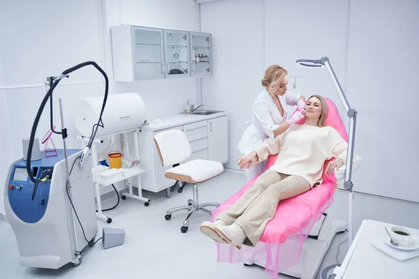 Médico de salón de belleza minimizando las líneas de sonrisa en la cara femenina — Foto de Stock