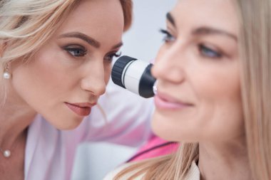 Konsantre orta yaşlı bayan doktor dermoskopi prosedürü uyguluyor.