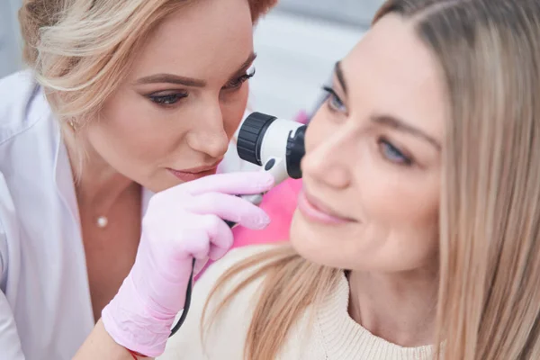 Experienced Caucasian female dermatologist performing dermatoscopy procedure — Stock Photo, Image