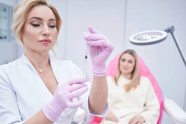 Concentrated dermatologist preparing for administering injection to patient — Stock Photo, Image