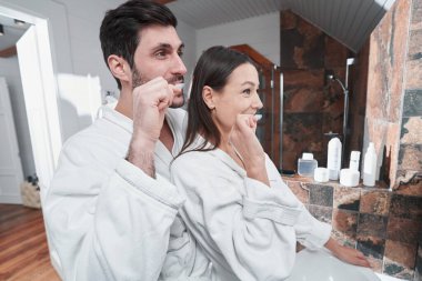 İnsanlar otelde aynanın önünde dişlerini fırçalıyorlar.