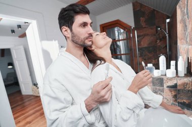 Dişlerini fırçalarken kocasına yaslanan mutlu kadın.