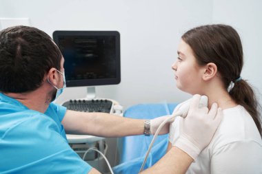 Tiroid bezini ultrason makinesiyle muayene eden bir tıp çalışanı.