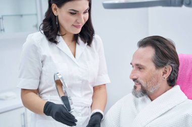 Güzel genç güzellik ustası aynayı tutuyor.