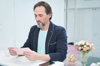 Yakışıklı yetişkin adam hediye kartına bakıyor.