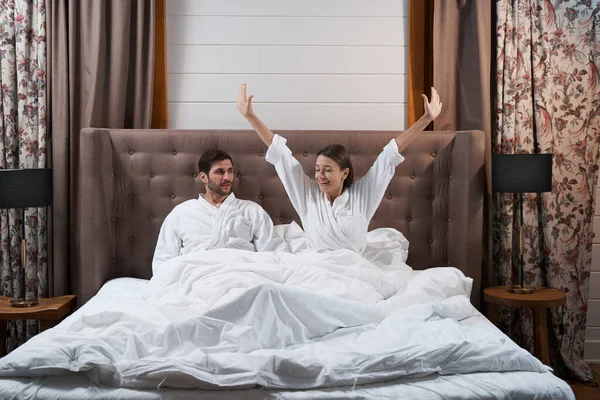 Woman waking up in hotel bed near husband — Fotografia de Stock