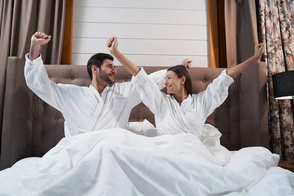 Married couple stretching in bed of hotel room — 스톡 사진