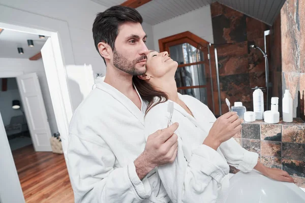 Dişlerini fırçalarken kocasına yaslanan mutlu kadın.