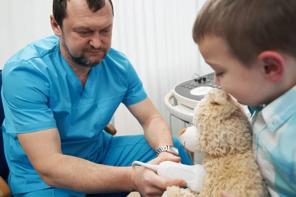 Caring medical worker examining the boy and his teddy bear — Stock Photo, Image