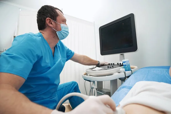 Caucasian doctor performing an ultrasound of the internal organs on monitor — стоковое фото