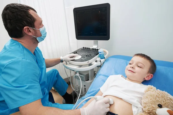 Medico premuroso che esamina il piccolo ragazzo con un'ecografia — Foto Stock