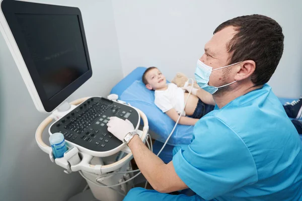 Médico cuidador que realiza un examen por ultrasonido del estómago de un niño —  Fotos de Stock