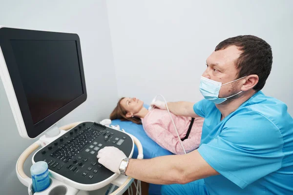 Caring endocrinologist performing an ultrasound examination of woman thyroid gland — стоковое фото