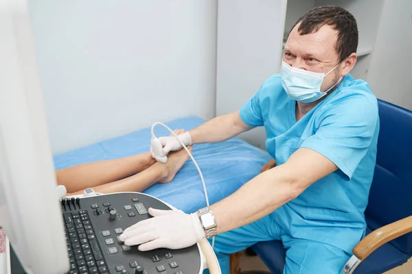 Profesional de la salud examinando la articulación del tobillo con un ultrasonido — Foto de Stock