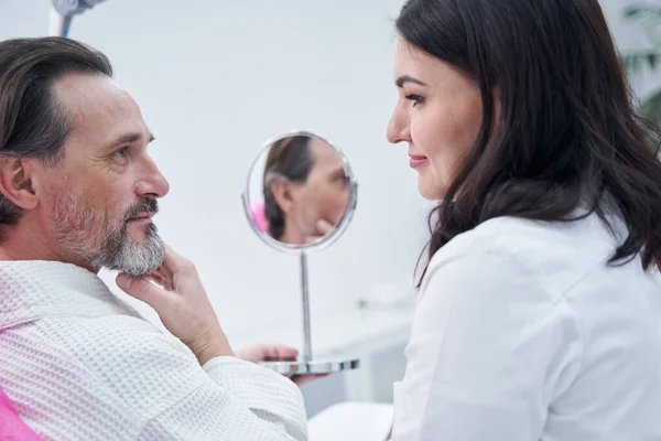 Молодой косметолог консультирует своего пациента — стоковое фото