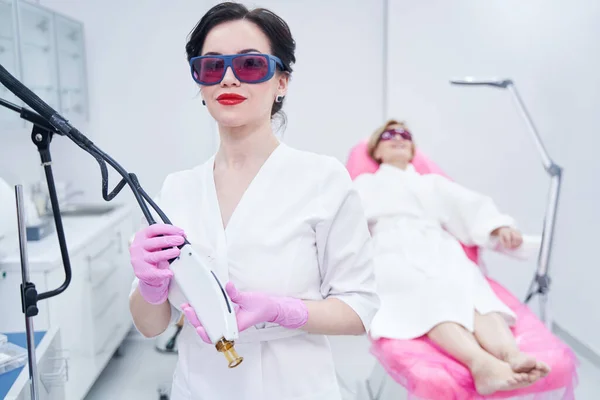 Female beautician in safety glasses holding alexandrite laser device — Foto Stock