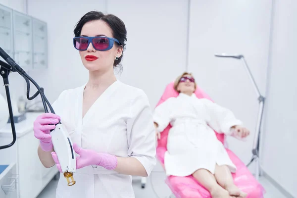 Kvinna kosmetolog håller alexandrit laser anordning i skönhetssalong — Stockfoto