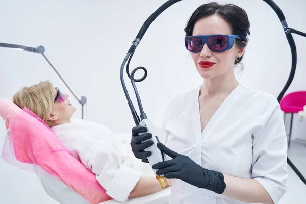 Kvinna kosmetolog i skyddsglasögon med alexandrit laser anordning — Stockfoto
