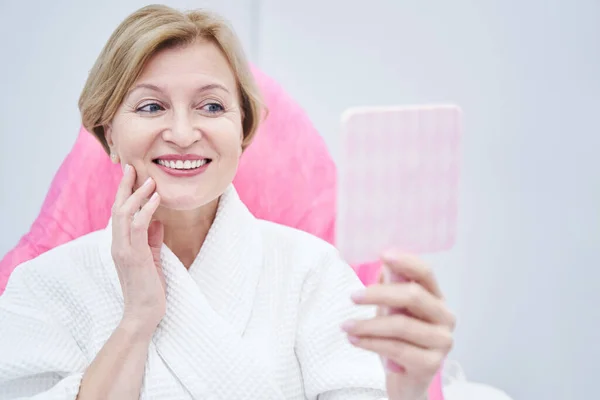 Cheerful woman looking in the mirror in beauty salon — ストック写真