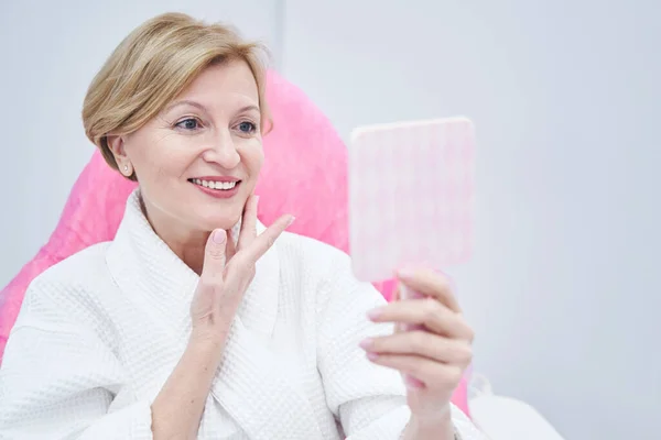 Femme heureuse regardant dans le miroir dans le salon de beauté — Photo