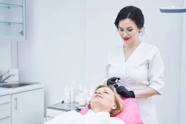 Kvinnlig tricholog som injicerar i kvinnlig hårbotten i skönhetscentret — Stockfoto